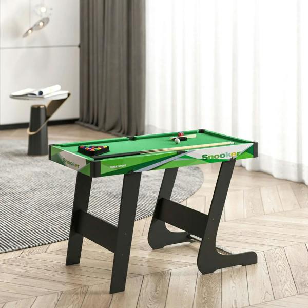 Green mini pool table set with balls and cues on a living room rug