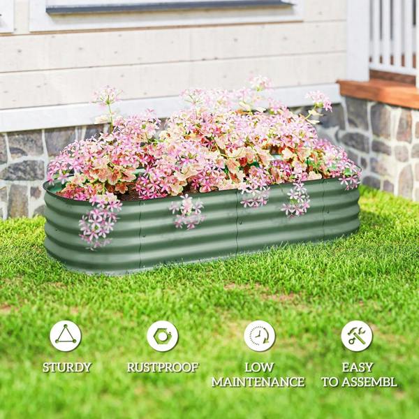 Green metal raised garden bed in a yard with pink flowering plants on grass