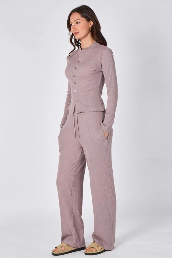 Woman wearing a matching long-sleeve top and pants set on a white background