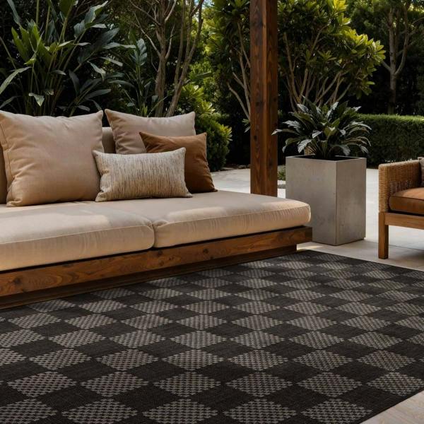 Outdoor seating area with a beige sofa, cushions, and a patterned rug.