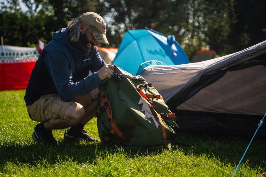 Image of a man looking through his rucksack whilst by the side of his Stafford 2.0 OLPRO & Ed Stafford 2 berth tent.