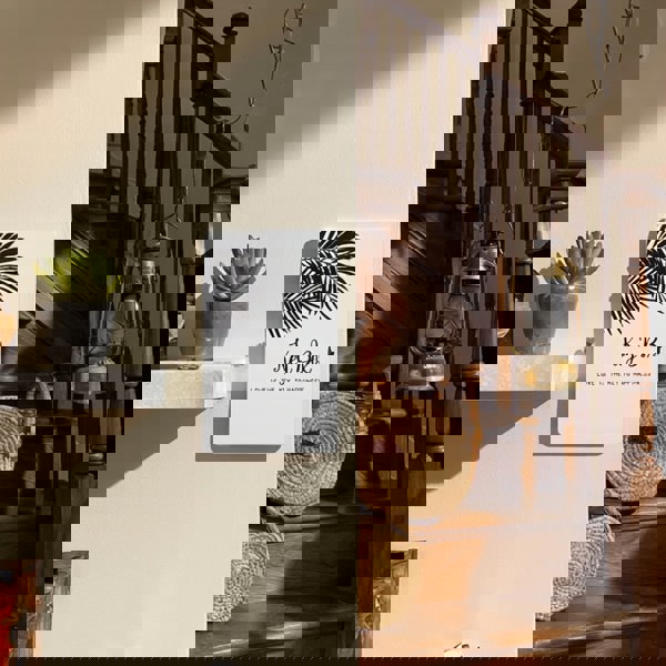 Key box with leaf design on a wall next to a wooden staircase with lanterns.