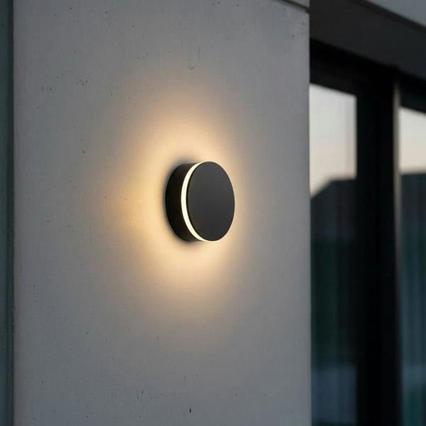 black LED outdoor wall lamp mounted on a concrete wall outside of a modern house 