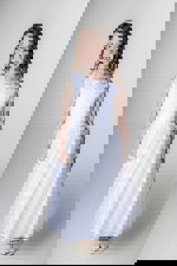 Young girl wearing a white dress against a plain background