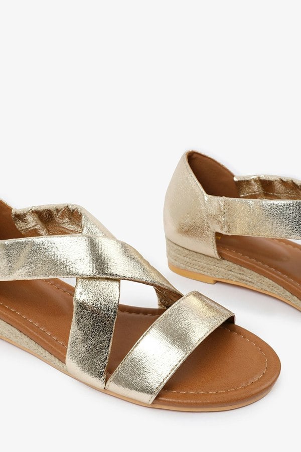 Where's That From Hummingbird Wide Fit Low Wedge Shoes With Cross Over Strap in Gold Metallic