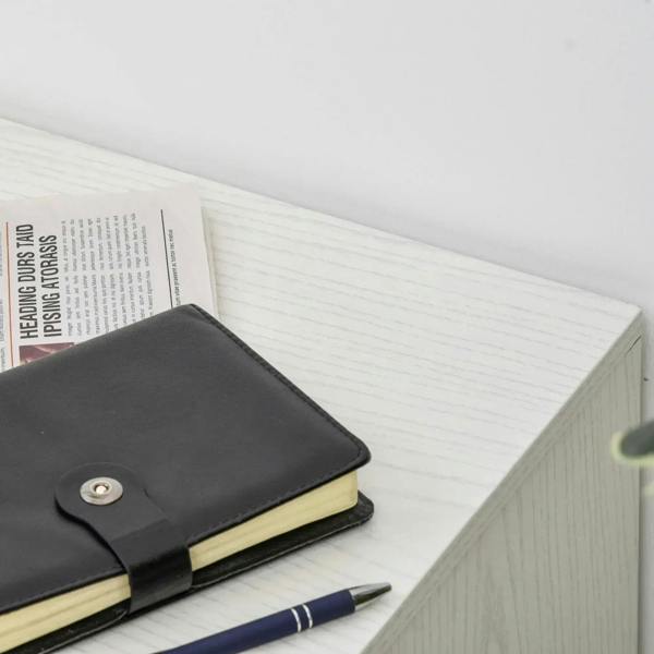 Close-up of top surface with black notebook next to a white woodgrain cabinet