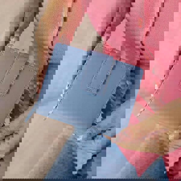 Person holding soft blue leather trifold purse with secure tab fastening