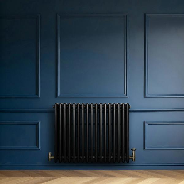 Traditional black 4 column radiator against a deep blue wall, featuring a sleek design with smooth, rounded edges and brass fittings