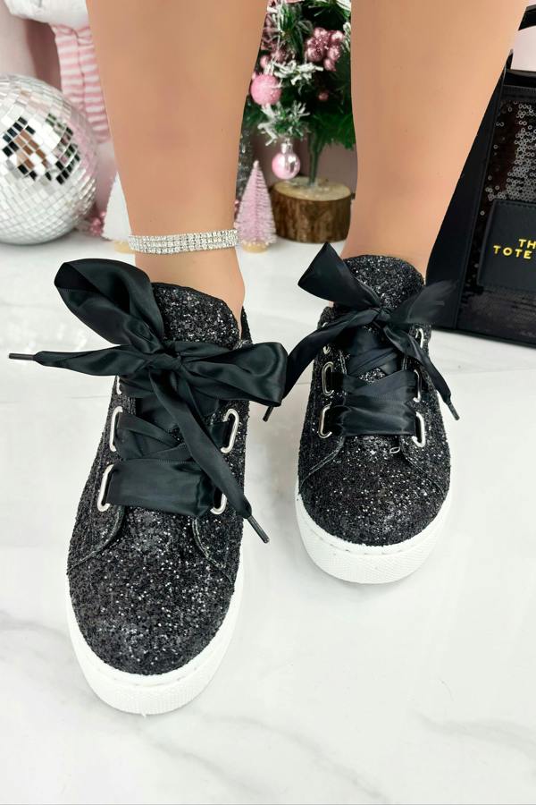 Black glittery sneakers with black ribbons on a white surface.