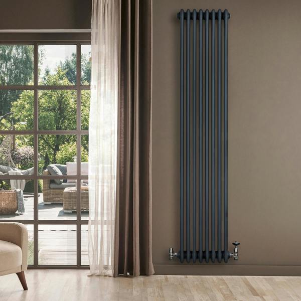 Traditional 4 column radiator in anthracite grey, tall and slim design, mounted on a wall beside a large window with natural light