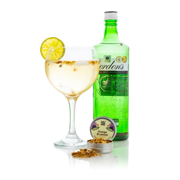 A Glass of Gin Infused with Natural & Noble Citrus Peel Next To a Bottle of Gin.