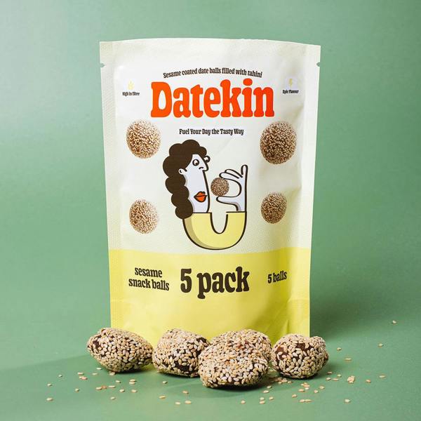 Datekin sesame snack balls packaging surrounded by sesame coated date balls on a green background