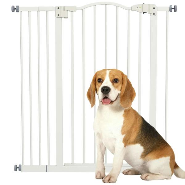 White pressure-fit dog safety gate with vertical bars and top latch, indoors with dog