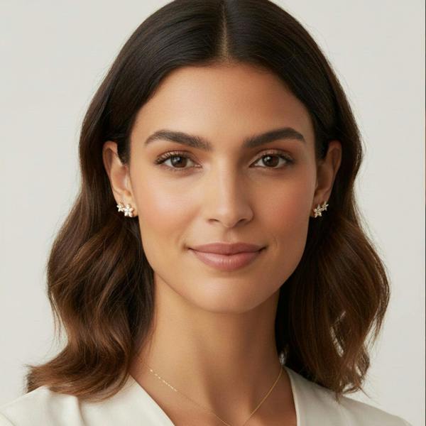 Woman with styled hair and a white top on a plain background
