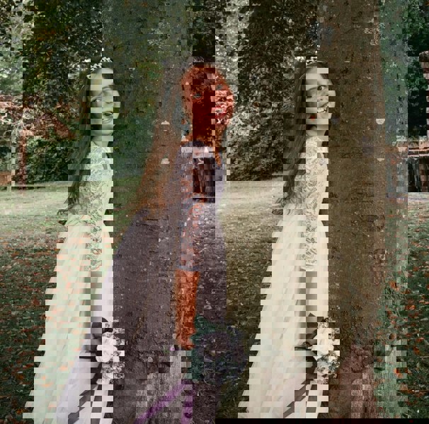 young girl holding flowers by tree