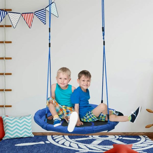 Blue hanging nest swing seat with two children indoors on a patterned play mat