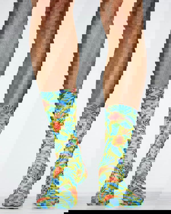 Colorful tropical patterned socks worn by a person on a white background