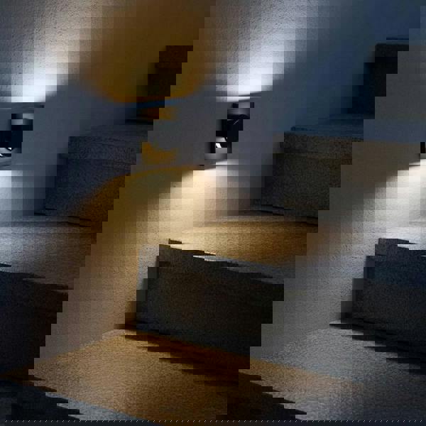 black recessed outdoor wall light mounted on the wall next to some outdoor concrete steps 