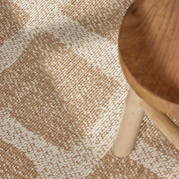 Close-up of a textured beige and brown carpet with a wooden chair leg.