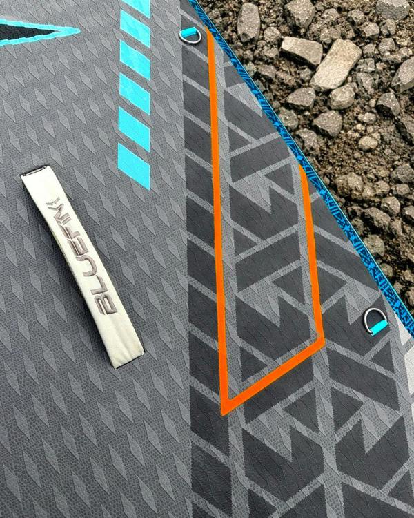 Inflatable paddleboard with gray textured surface, blue and orange graphics, and a metal D-ring.