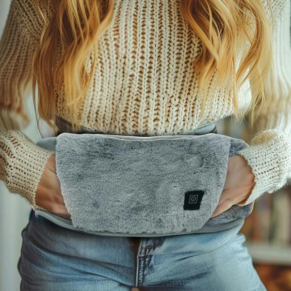 A woman wearing a grey faux-fur therapeutic heated belt over a cream knitted jumper.
