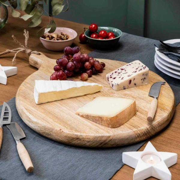 A thick, round natural mango wood serving board with a solid paddle handle and a rustic jute rope hanging loop, showcasing rich wooden grain.