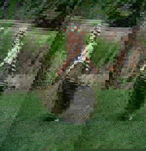 Pretty girl standing in a park playing with skirt
