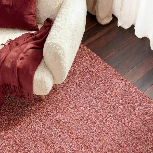 Red textured rug in a room with a white sofa and red cushions.