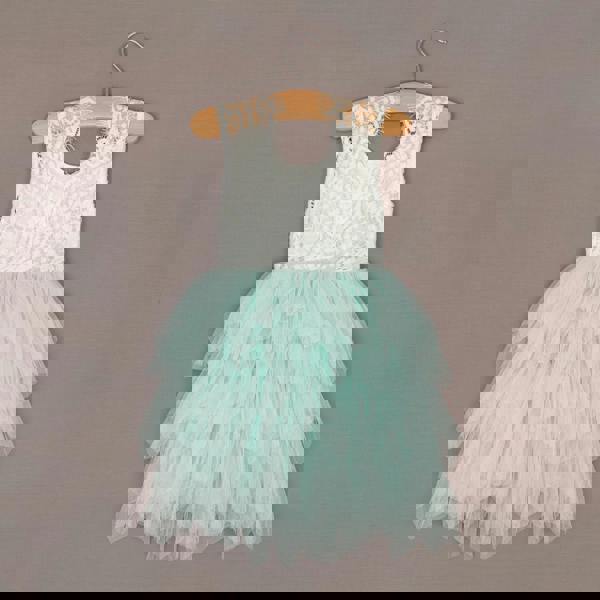 White lace top and mint green tutu skirt dress on a hanger against a brown background