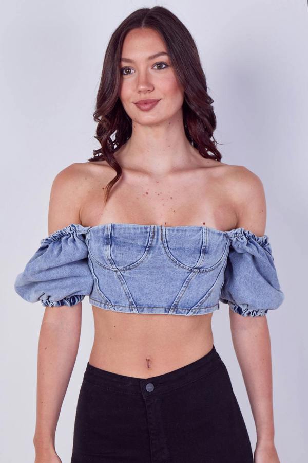 Woman wearing a denim off-shoulder top against a plain background