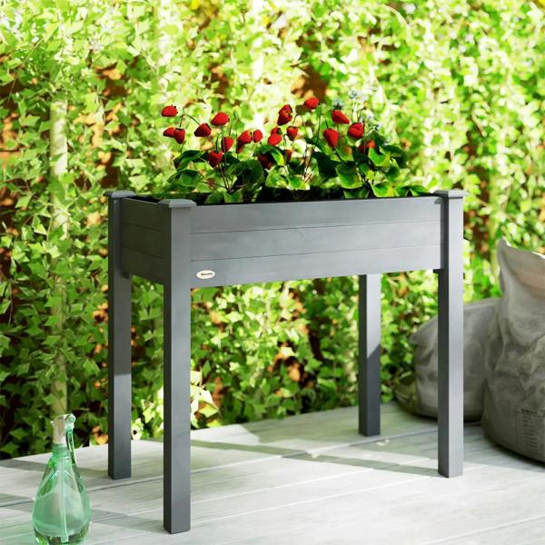 Dark grey raised planter box with green plants and open bed top.