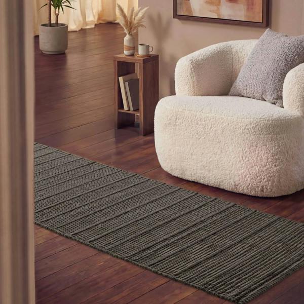 Living room with a textured gray rug, white sofa, and wooden side table.