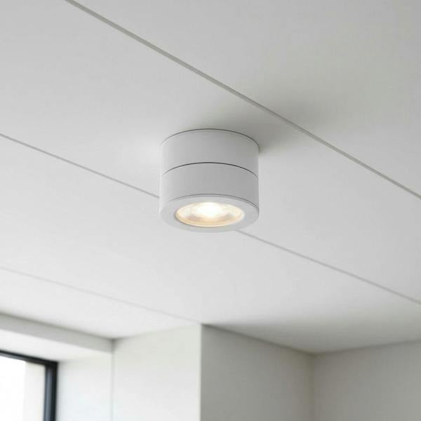 white surface mount adjustable spotlight installed on a white ceiling in a modern house