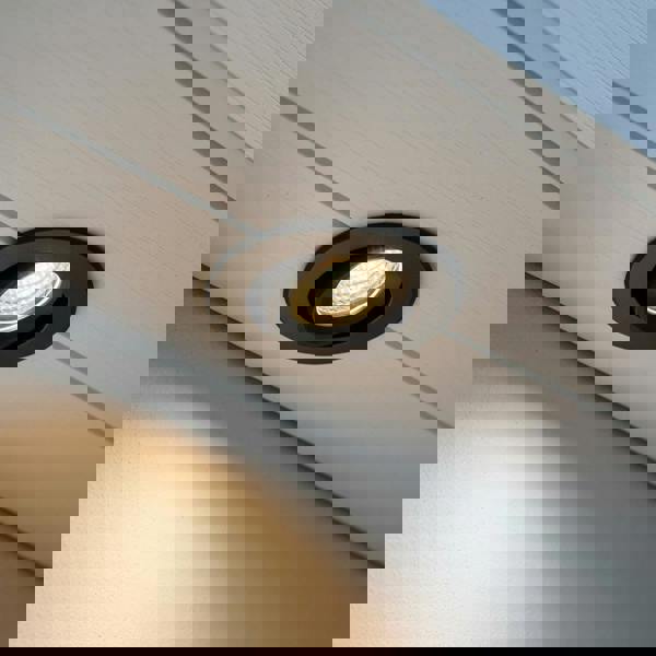 black adjustable soffit light mounted in the white soffit of a house