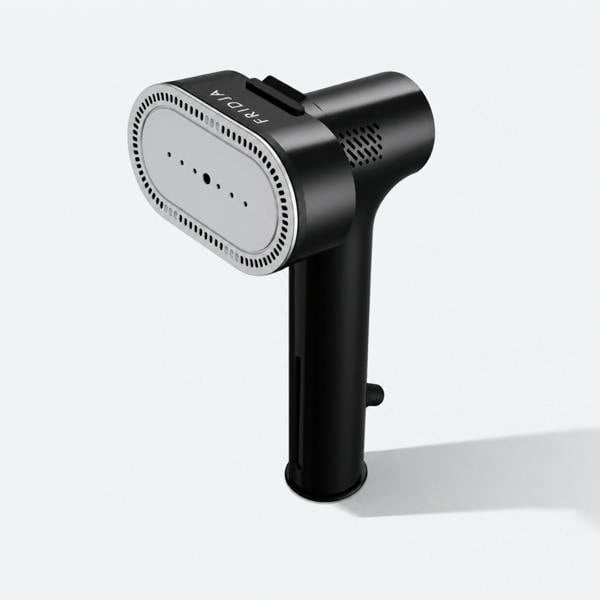 The Fridja f20 Handheld Clothes Steamer Pro with Suction, featuring a sleek black body and a silver steam plate, stands upright on a light gray background while casting a gentle shadow to the right. The “Fridja” brand name is displayed at the top, emphasizing its modern design as an ideal portable iron and versatile handheld clothes steamer for effortless wrinkle removal.