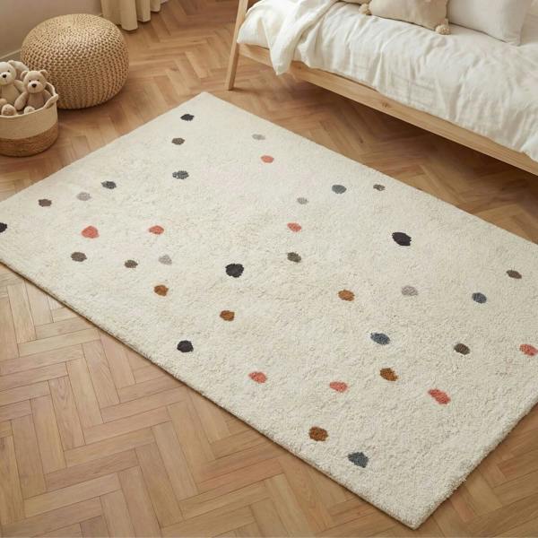 Beige rug with multicolored dots on a wooden floor