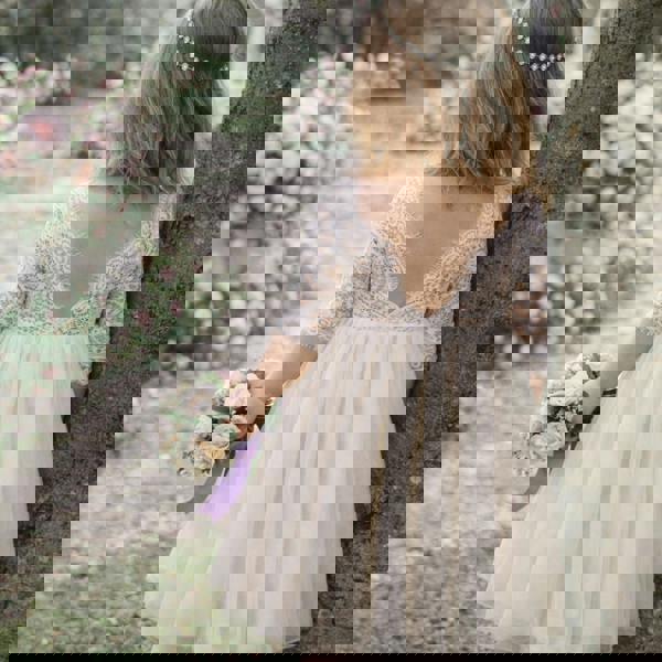 toddler in a lace dress holding a bouquet in a garden setting