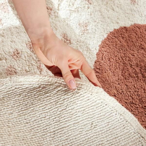 Hand touching a textured beige and brown rug