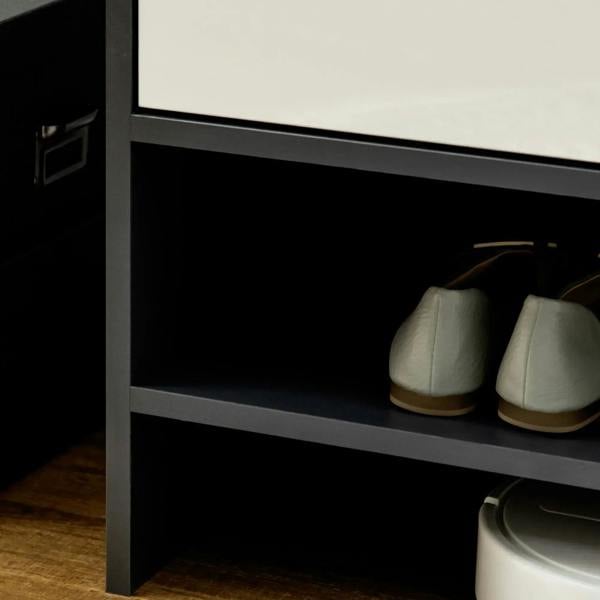 Open lower shelf of a grey shoe cabinet with two light-colored shoes inside
