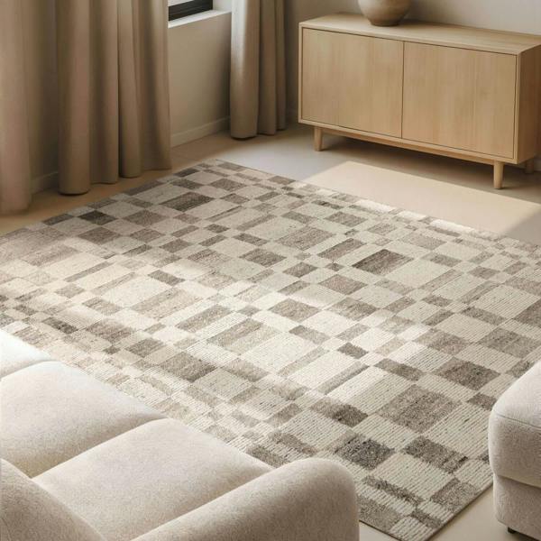 Patterned rug on a floor with a beige sofa and wooden cabinet in the background