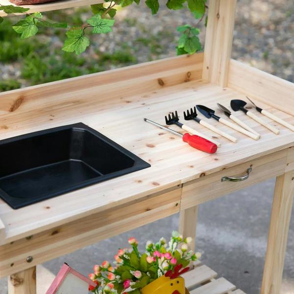 Wood potting bench close-up with black sink basin and gardening tools on the top