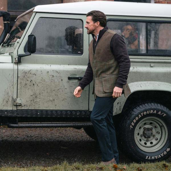Hoggs of Fife Kingussie Technical Tweed Field Waistcoat worn outdoors beside Land Rover in wet countryside setting