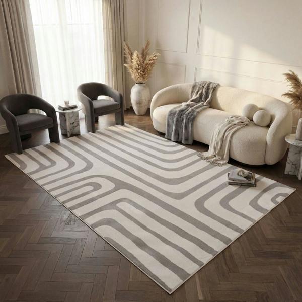 Modern living room with a patterned rug, sofa, and chairs.