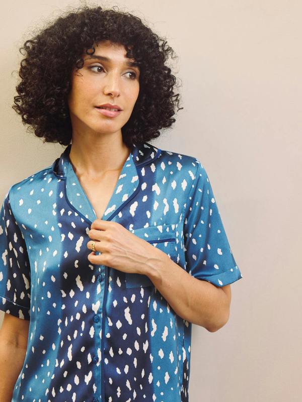 Woman wearing a blue patterned pyjama shirt against a plain background