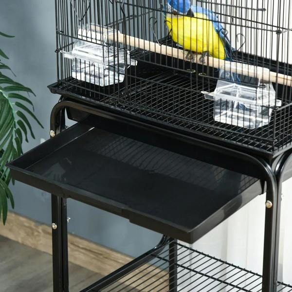 Close-up of black slide-out dropping tray on bird cage stand with metal wire bars