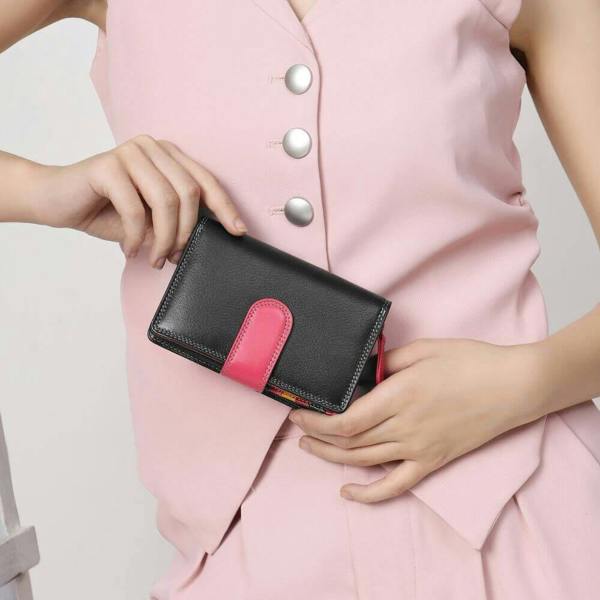 Person holding a black wallet with an pink strap against a white background