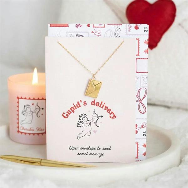 Gold locket necklace resting on a Cupid-themed greeting card with envelope art