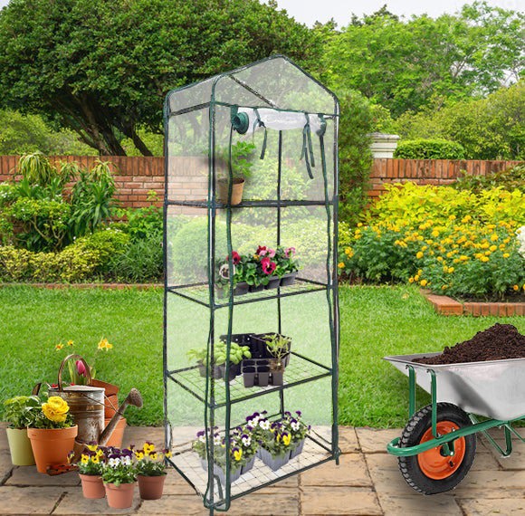 Mini greenhouse with four tiers, clear plastic cover, and sturdy metal frame, set in a vibrant garden with potted plants and a wheelbarrow