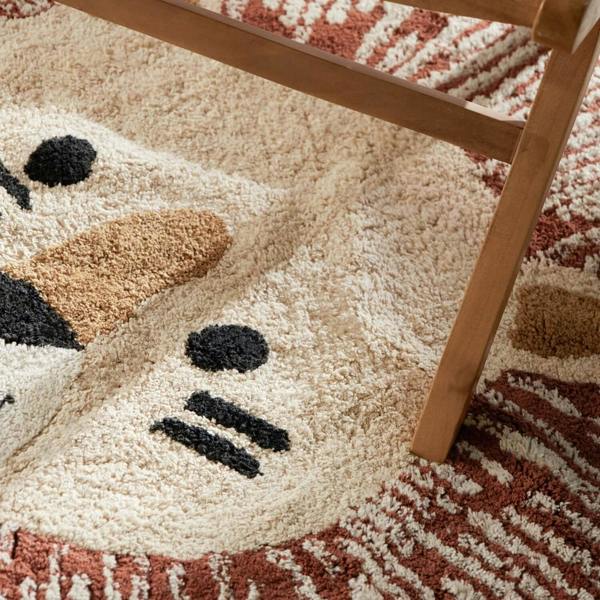 Close-up of a textured rug with a snowman design and a wooden chair leg.