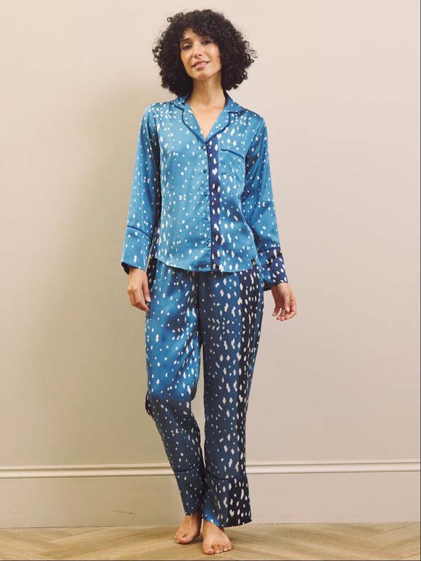 Woman wearing blue and white fawn patterned pyjamas against a beige wall.